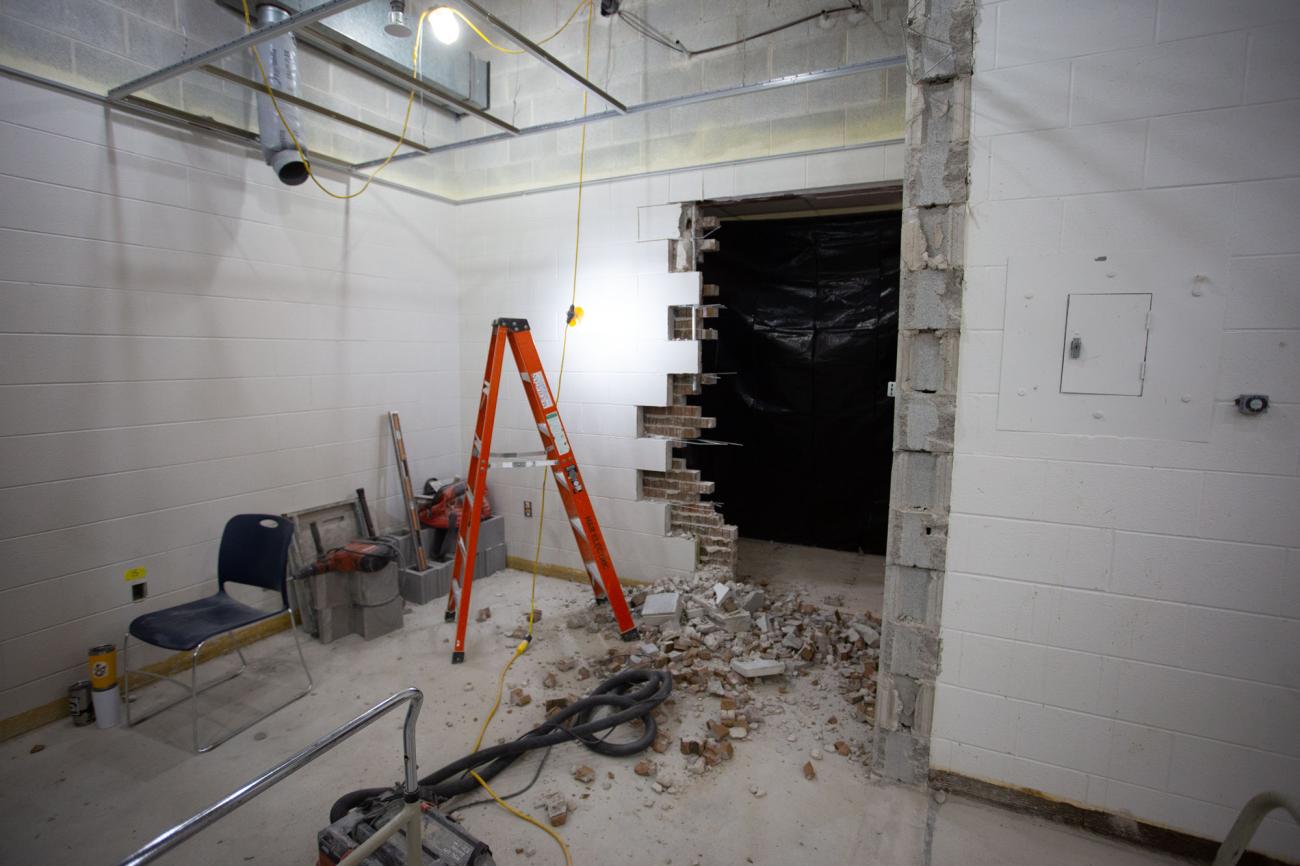 A hole in a cinder block wall with debris on the floor