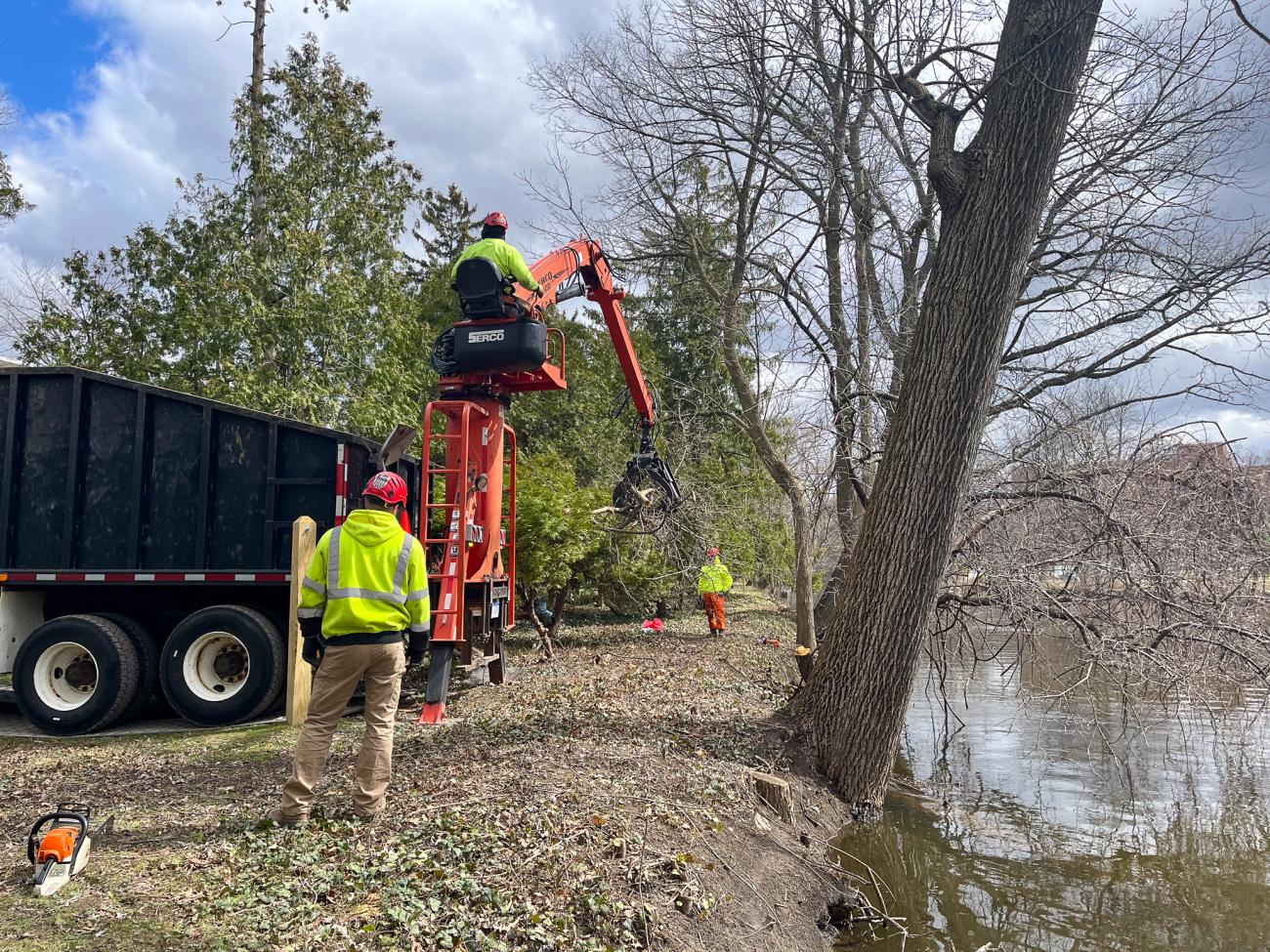 A large claw vehicle parked next to the Red Cedar River