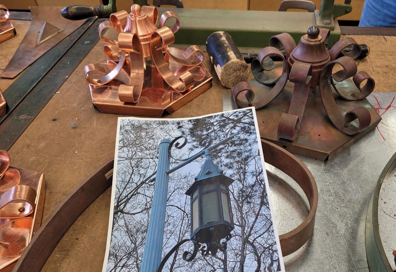 An old lantern decorative copper piece next to a new one and a photo of an existing lantern