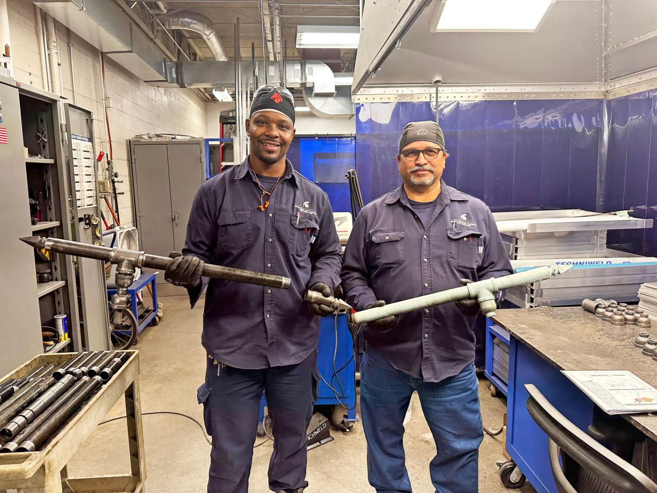 Two metalworkers smile at the camera