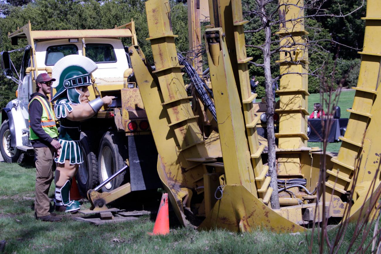 The Sparty mascot oversees the planting of a tree on MSU's campus.