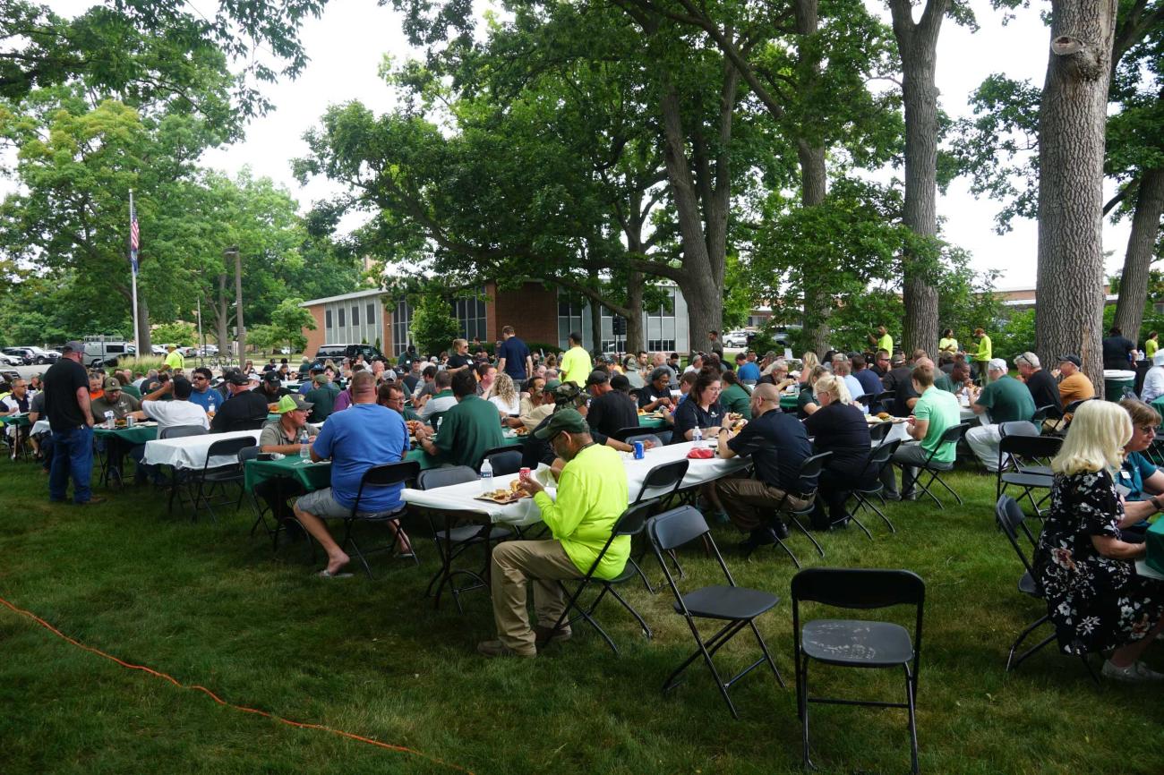 Many people sitting outside at tables eating lunch on a cloudy day