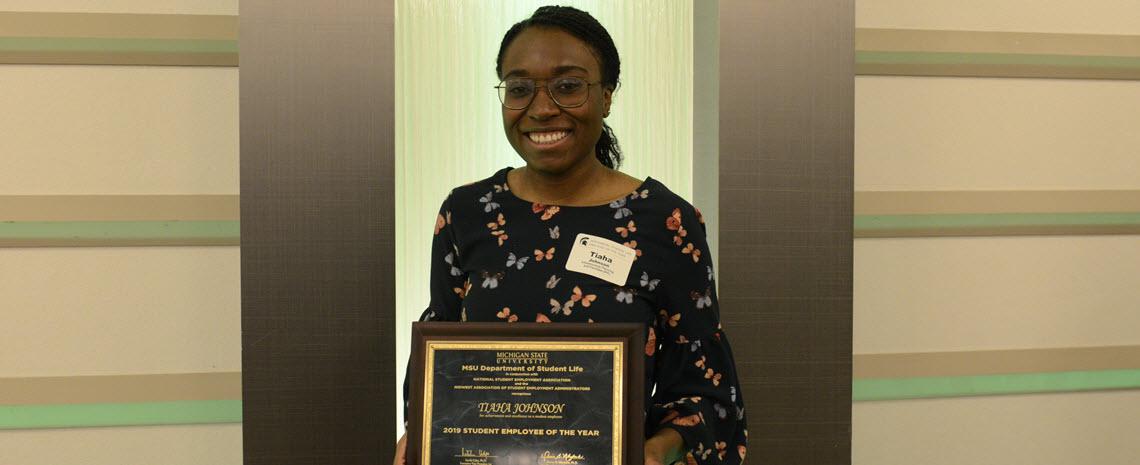 Photo of Tiaha Johnson holding her student employee of the year plaque
