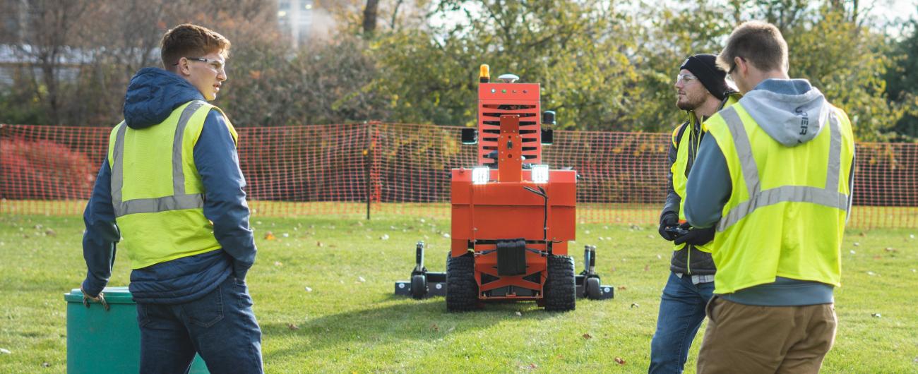 Engineering students testing mowbot in the grass near the IPF building