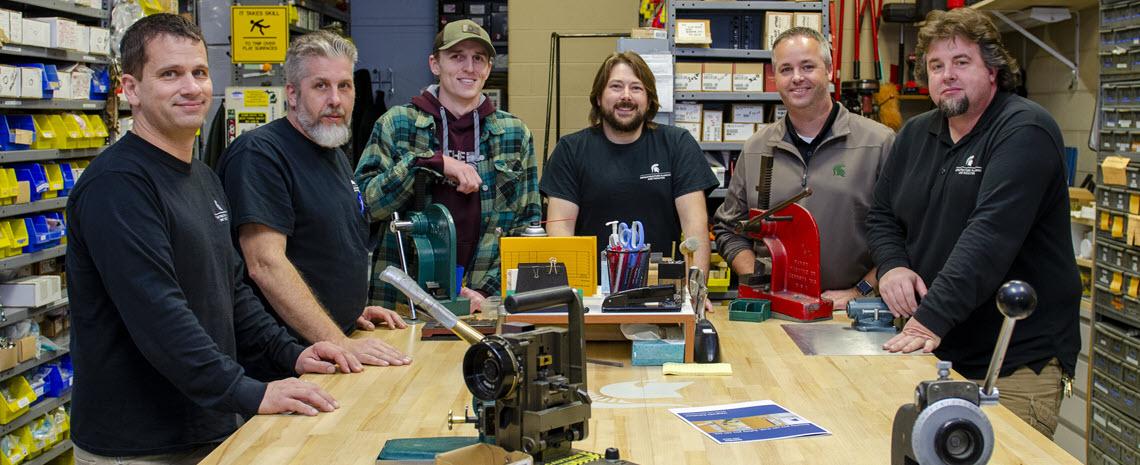 Photo of the key shop crew standing around a workbench