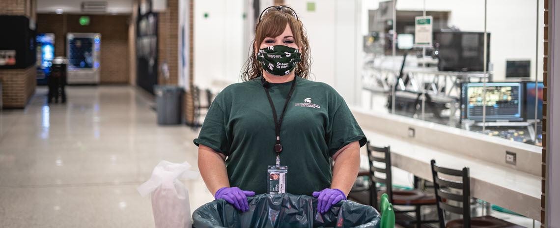 Sarah Halsey standing in Communication Arts and Sciences with face mask and work cart