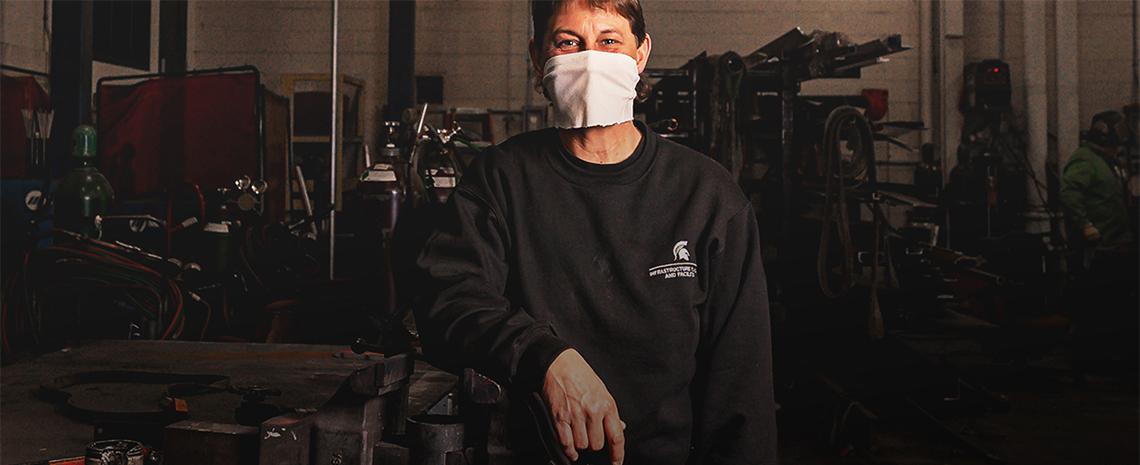 Marcie Nickols stands holding a large wrench inside the IPF Building