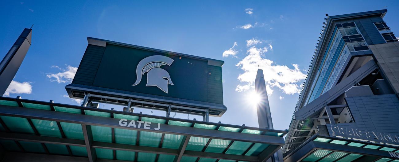 Large sign on Spartan Stadium with the Spartan helmet framed by a blue sky and wispy clouds
