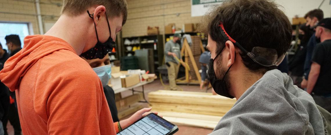 Two students look at technical specs on a tablet.