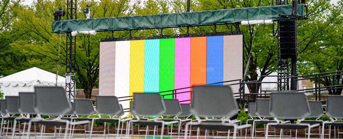 An empty stage with chairs and a screen displaying test color bars.