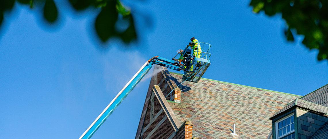 an IPF worker power washes a stone building from a crane