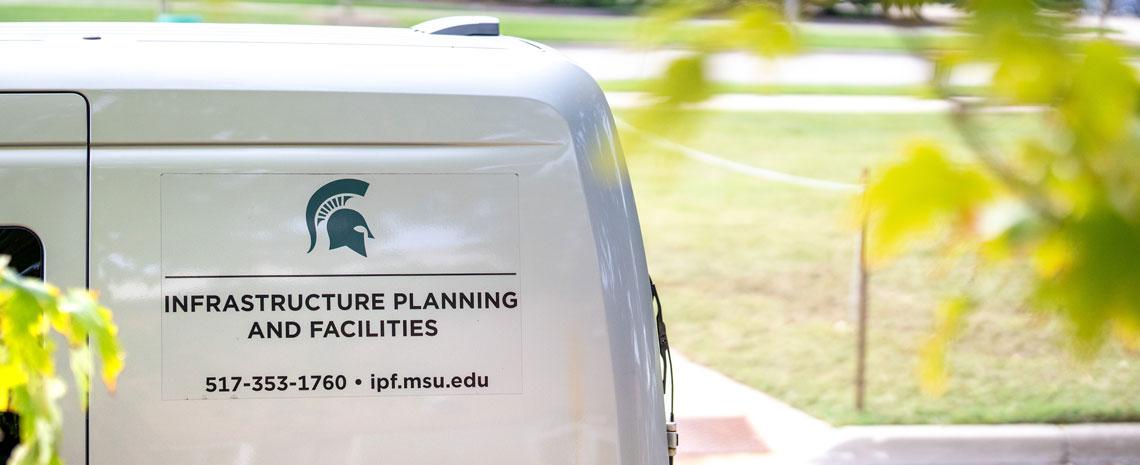 A white IPF van parked among green foliage