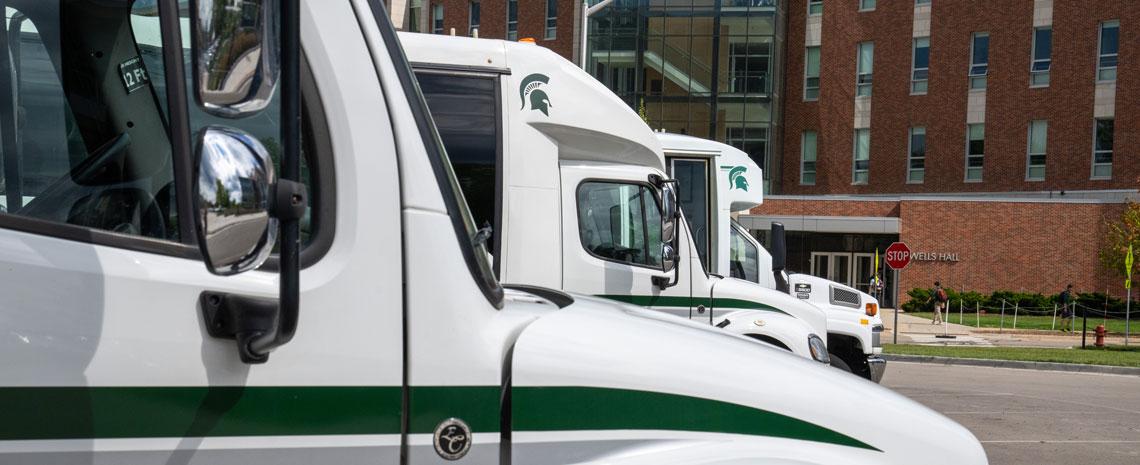 Three MSU fleet vehicles parked in front of Wells Hall