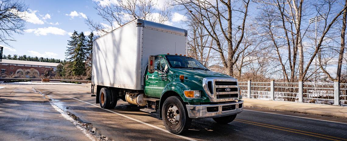 A green MSU truck in front of Sparty Statue