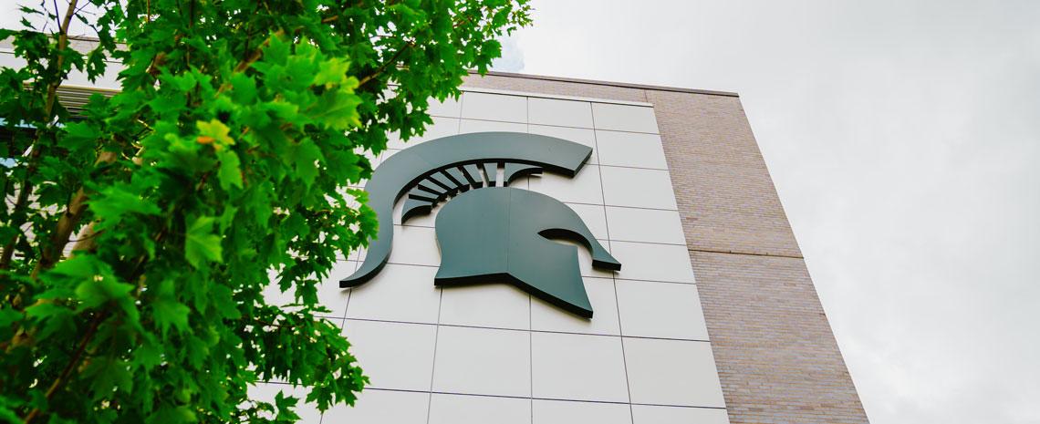 Side of a building on campus with a large Spartan helmet