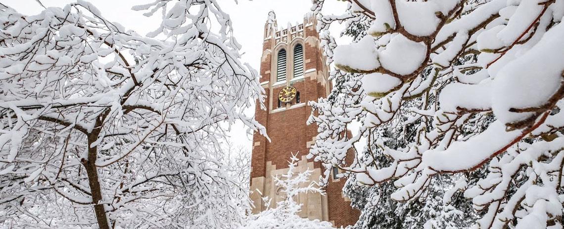 Beaumont Tower surrounded by bare tree branches covered in snow