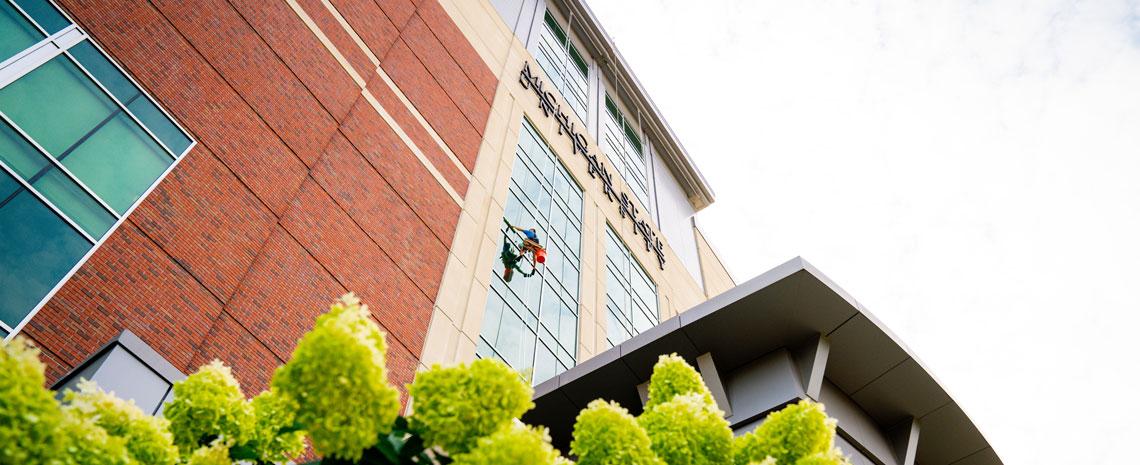 Exterior of MSU stadium admin offices with a window cleaner