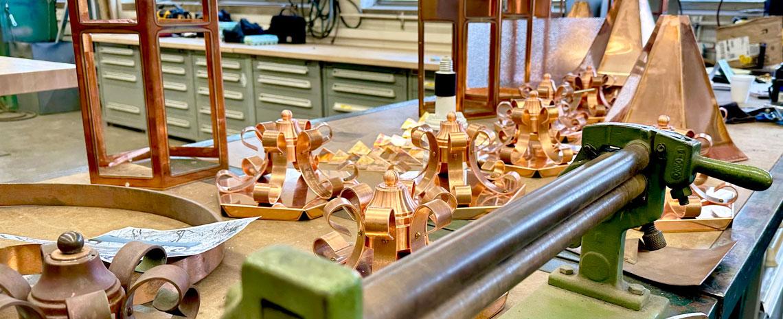 Pieces of unfinished copper lanterns on a workbench