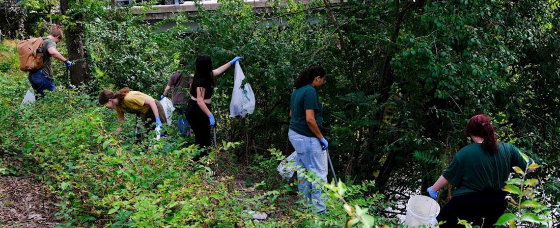 Volunteers on the Red Cedar riverbank with garbage bags and grabbers