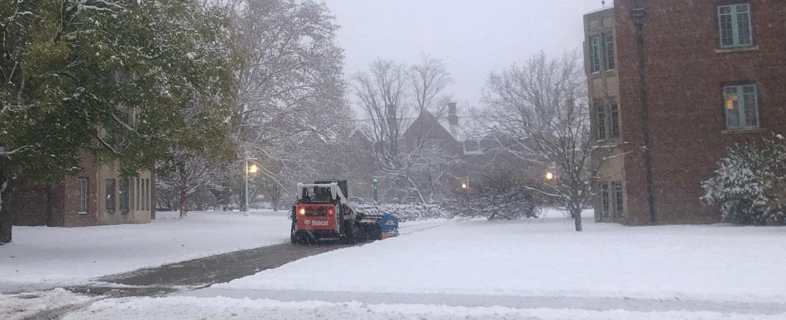 A motorized snowplow clears snow from a walkway