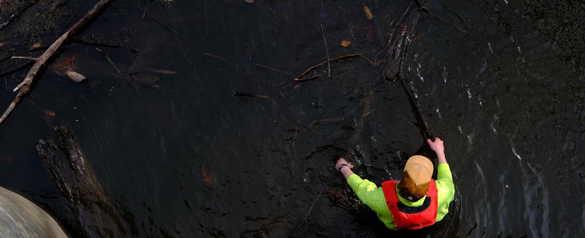 An IPF worker clears wood and debris from the Red Cedar River