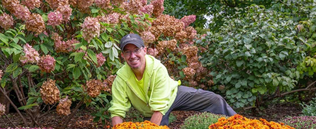 Kevin Dylong planting flowers amongst bushes on the MSU campus