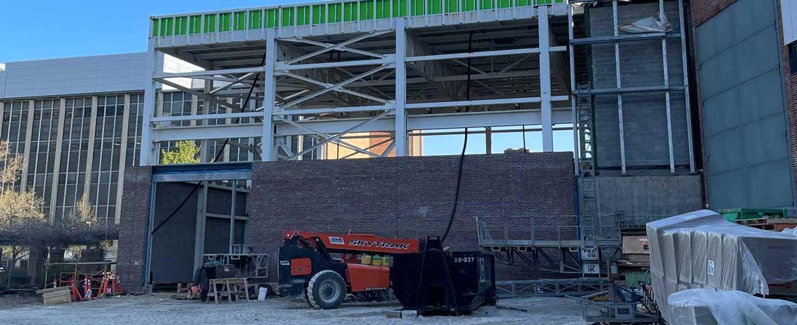 Exterior construction area with a cherry picker, building materials and brick and steel beams