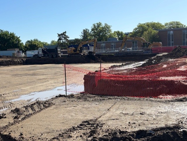 construction area with orange netting and large machinery in background